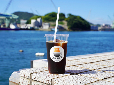 海が背景にアイスコーヒーがメインに写っている写真です